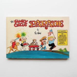 May include: A vintage copy of "The Family Circus Parade" by Bil Keane. The cover features a parade scene with cartoon characters, a red wagon, and an American flag. The title is in a decorative font, with the text "A Happy Procession of Selected Cartoons Featuring America's Favorite Comic Family."