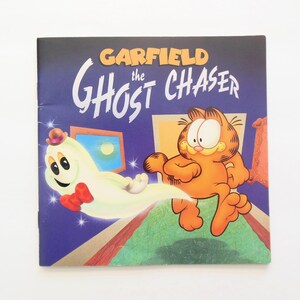 May include: A book cover featuring Garfield the cat chasing a ghost. The book title is "Garfield the Ghost Chaser".