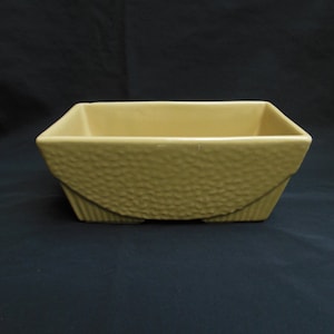 May include: A rectangular ceramic planter with a textured surface in a light brown color.