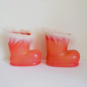 May include: Two orange plastic Santa boots with white faux fur trim. The boots are empty and ready to be filled with treats.