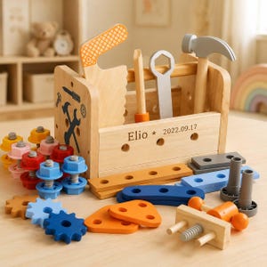 May include: A wooden toy toolbox containing a saw, wrench, and hammer, with the name Elio and the date 2022.09.17 engraved on the front. The set includes various colorful plastic bolts, nuts, gears, and wooden construction pieces in blue, orange, and gray.