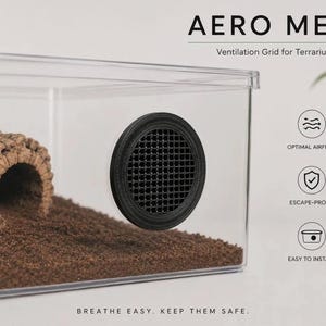 Könnte beinhalten: Ein durchsichtiges Kunststoff-Terrarium mit einem runden, schwarzen Aero Mesh-Lüftungsgitter. Im Inneren sind braunes Substrat und ein zylindrisches Korkrinden-Versteck zu sehen. Text: AERO MESH, Ventilation Grid for Terrariums, BREATHE EASY.