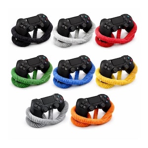 Könnte beinhalten: Eine Sammlung schwarzer Gamecontroller, jeweils umgeben von einem dicken, gewickelten Seil in verschiedenen Farben: Schwarz, Grau, Rot, Grün, Blau, Gelb und Orange. Die Controller sind auf weißem Hintergrund angeordnet.
