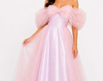 May include: A floor-length gown in a soft pastel pink hue, featuring an off-the-shoulder neckline with voluminous, sheer tulle puff sleeves. A large, structured tulle bow is centered at the bodice, and the skirt is made of layered tulle.
