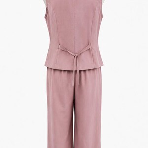 May include: A dusty rose two-piece set consisting of a sleeveless vest and wide-leg trousers. The vest features a notched collar and a thin tie-back detail at the waist. The trousers have a straight-cut silhouette and a clean, solid-colored finish.