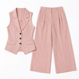 May include: A dusty pink two-piece set consisting of a sleeveless vest and wide-leg trousers. The vest features a notched lapel, three black buttons, and two front flap pockets. The trousers have a high waist with pleats and a wide-leg cut.