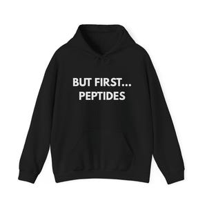 Puede incluir: Sudadera con capucha negra con el texto blanco "BUT FIRST... PEPTIDES". La sudadera tiene un bolsillo delantero y una capucha con cordón. La prenda está hecha de un material suave y cómodo.