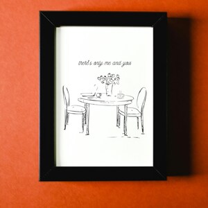 Puede incluir: Lámina artística enmarcada en negro con un boceto de una mesa para dos con flores, una taza de café y el texto "there's only me and you". La obra de arte es en blanco y negro, sobre un fondo naranja.