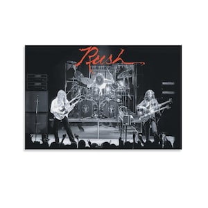 Könnte beinhalten: Schwarz-Weiß-Fotografie der Band Rush bei einem Live-Auftritt auf der Bühne. Die Bandmitglieder spielen Gitarre und Schlagzeug. Der Name der Band, "Rush", ist in roter Schrift oben im Bild geschrieben. Im Vordergrund ist eine Menschenmenge zu sehen.