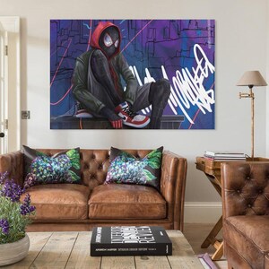 May include: A large canvas art print featuring a superhero in a black and red suit, seated with a cityscape backdrop. The artwork has a graffiti-style aesthetic with vibrant colors and bold lines. The superhero is wearing red and white sneakers.