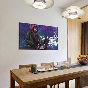 May include: A canvas print featuring a stylized illustration of a superhero in a red hoodie and black mask, seated against a graffiti-covered background. The artwork showcases a vibrant color palette with shades of purple, blue, and red, and is displayed in a dining room.