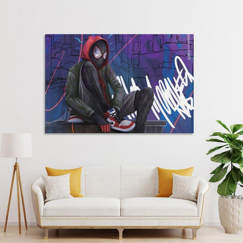 May include: A framed art print featuring a character in a black and red suit with a red hood, seated against a purple and blue graffiti background. The character wears red, white, and black sneakers. The artwork is displayed above a white sofa.