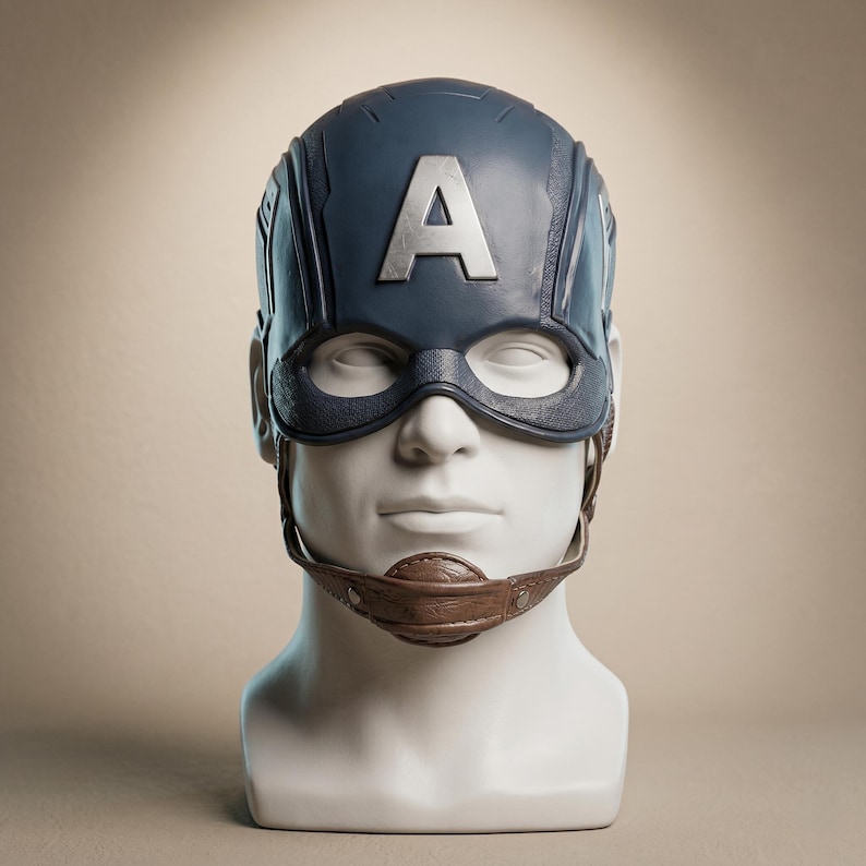 May include: A Captain America helmet replica, featuring a dark blue design with a large silver "A" on the forehead. The mask includes a dark blue eye covering and a brown chin strap, displayed on a white mannequin head.