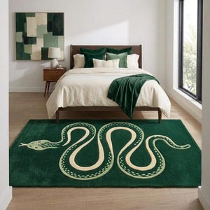 May include: A rectangular area rug featuring a large, stylised snake motif in cream and light green on a deep forest green background. The snake is depicted in a winding, serpentine shape that spans the length of the rug, centred on the floor.