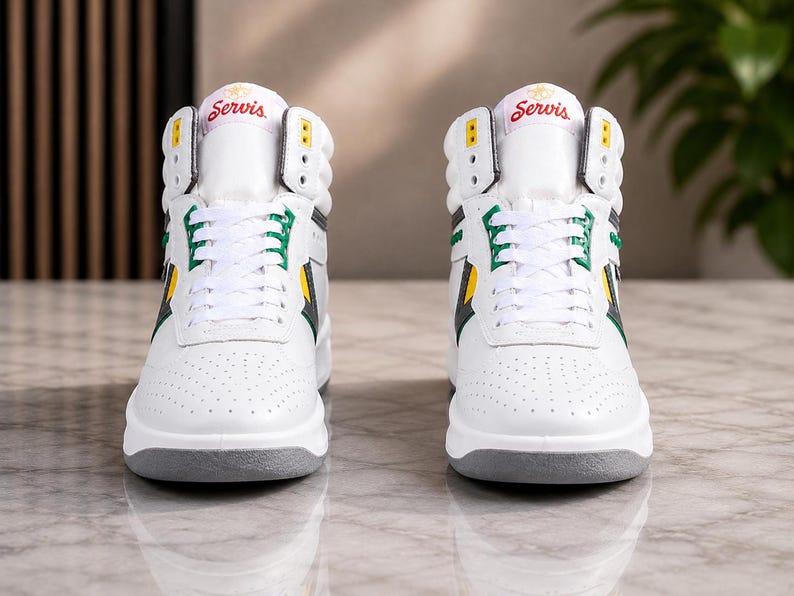 Puede incluir: Un par de zapatillas altas blancas con detalles en verde y amarillo. Las zapatillas tienen una suela gris y la palabra "Servis" en rojo en la leng&uuml;eta. El dise&ntilde;o incluye una puntera perforada y cierre con cordones.