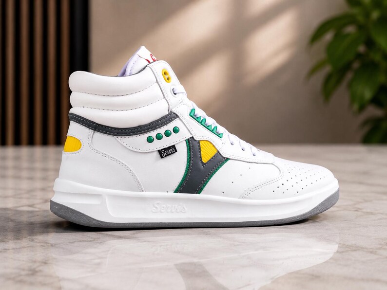 Puede incluir: Zapatilla alta blanca con detalles grises, amarillos y verdes. La zapatilla presenta la marca "Serra's" y un dise&ntilde;o perforado en la puntera. La suela es gris.