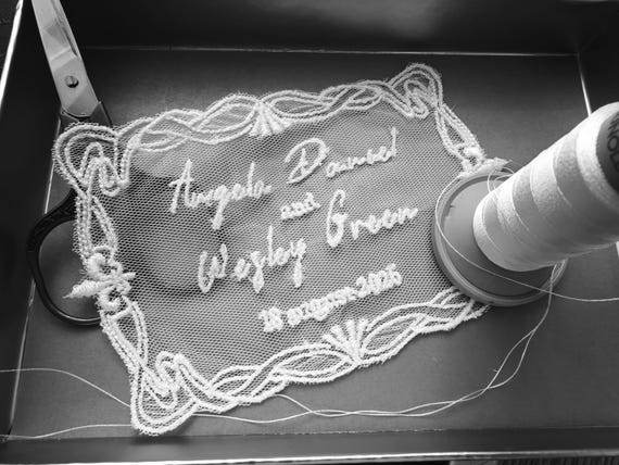 Save-the-date announcements actually embroidered onto sheer tulle/lace — a genuinely tactile, heirloom-quality alternative to paper that guests will never throw away.