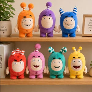 May include: A collection of seven plush monster toys in various colours including orange, purple, blue, red, pink, teal, and yellow. Each creature features a rounded body, two antennae or horns, and a distinct facial expression with visible teeth.