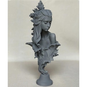 Puede incluir: Busto gris de una mujer con cabello largo y ondeado y una corona de hojas. La escultura presenta un diseño detallado con una expresión serena y está montada sobre un pedestal. El busto es una pieza de arte decorativa.