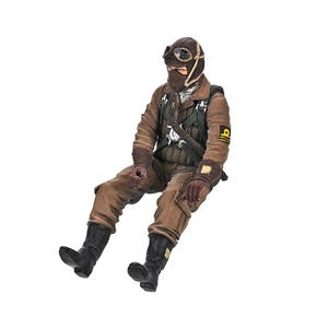 May include: A miniature figurine of a seated vintage pilot, dressed in a brown flight suit, goggles, and a leather helmet. The figure has black boots and gloves, and a detailed harness. The pilot is posed as if seated in a cockpit.