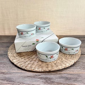 May include: A set of three white ceramic ramekins with vertical ribbing and a delicate floral vine pattern featuring pink flowers and green leaves. The box is labeled Savoir Vivre, Ultra Ceram, Spring Fantasy, Souffle Set 3B, and Japan.