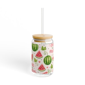 Op de afbeelding: Een heldere glazen beker met een bamboe deksel en een helder rietje. De beker is versierd met een watermeloenpatroon en de tekst "One in a melon". Het ontwerp bevat hele watermeloenen, watermeloenplakken en groene bladeren.