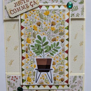 Peut inclure: Une carte de vœux artisanale avec un panneau central rectangulaire à motif floral jaune et une illustration de plante en pot. La carte comprend une étiquette avec le texte JUSTE COMME ÇA, des bordures triangulaires et deux petites gemmes vertes.