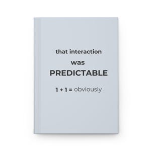May include: A light blue notebook with the text "that interaction was PREDICTABLE 1+1=obviously" printed in black. The notebook is rectangular and has a clean, minimalist design.