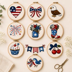 Peut inclure: Une collection de dix tambours à broder circulaires en bois présentant des motifs au point de croix sur le thème patriotique, incluant un cœur, un nœud, un aigle, des feux d'artifice, des fleurs en pot, une botte, un cupcake, une guirlande, des cerises et un oiseau.