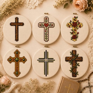 Peut inclure: Six tambours à broder circulaires présentant des motifs de croix sur tissu blanc. Les motifs incluent une croix en bois brun, une croix florale avec un cœur rouge, une croix jaune avec des roses rouges, une croix dorée avec des gemmes vertes, une croix rayée noire et verte, et une croix en bois brun entourée de vignes vertes.
