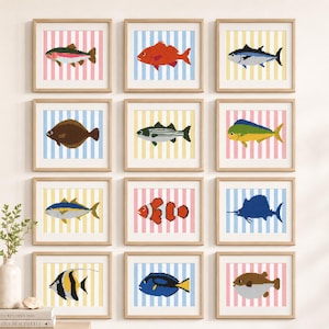 May include: A grid of twelve square framed wall art pieces, each featuring a pixel art fish illustration against a vertical striped background in pastel pink, blue, or yellow. The collection displays various fish species in distinct colors.