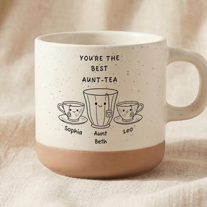 以下が含まれることがあります： 茶色のベースが付いたクリーム色のセラミックマグカップ。 「YOU'RE THE BEST AUNT-TEA」の文字とティーカップのイラストが特徴です。 マグカップにはハンドルがあり、Sophia、Aunt Beth、Leoという名前で飾られています。