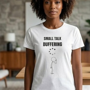 May include: A white t-shirt with the text "SMALL TALK BUFFERING" in black, along with a graphic of a stick figure and a loading symbol. The shirt is worn by a person in blue jeans.