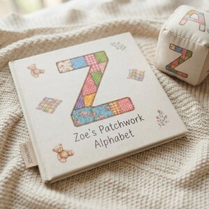 Puede incluir: Un libro cuadrado de tapa dura titulado Zoe's Patchwork Alphabet con una letra Z grande con un patr&oacute;n de patchwork colorido en la portada, acompa&ntilde;ado de ilustraciones de ositos de peluche y peque&ntilde;as colchas, junto a un cubo de tela con la letra A.