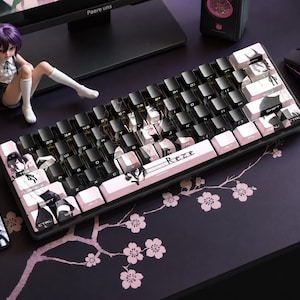 Könnte beinhalten: Eine schwarze und rosa mechanische Tastatur mit individuellen Tastenkappen, die Anime-Charaktere zeigen. Die Tastatur hat ein kompaktes Layout und eine rosa Leertaste mit dem Namen "Reze". Das Setup umfasst eine Maus, ein Mauspad und eine Figur.