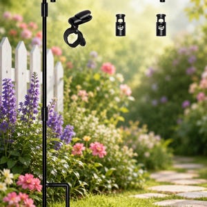 May include: A black metal garden flag stand featuring a horizontal crossbar with a decorative hook end, a vertical pole with a two-pronged ground stake, and three black plastic spring-loaded clips for securing flags to the metal frame.