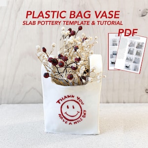 May include: A white ceramic vase shaped like a plastic bag, filled with dried flowers and berries. The vase has a red smiley face and the words "THANK YOU HAVE A NICE DAY". The image also includes a PDF tutorial.