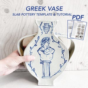 Può includere: Un vaso in ceramica con due manici caratterizzato da un'illustrazione blu dipinta a mano di un busto su un piedistallo circondato da una corona di foglie. Il testo GREEK VASE SLAB POTTERY TEMPLATE & TUTORIAL PDF è visibile.