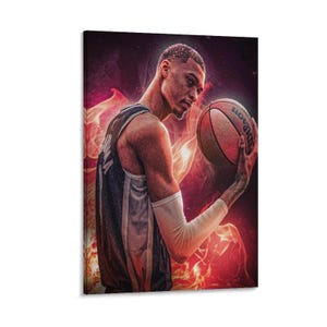 May include: A canvas print featuring a basketball player holding a Wilson basketball. The player is wearing a blue and white jersey and a white arm sleeve. The background is a fiery red and orange design.