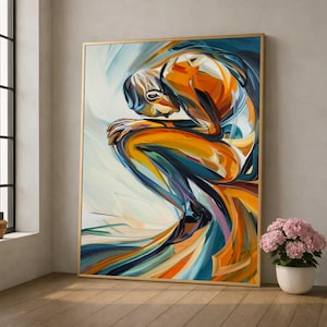 Puede incluir: Impresión artística abstracta que representa una figura sentada, representada en tonos vibrantes de naranja, azul y amarillo. La obra de arte está enmarcada en oro y se exhibe contra una pared neutra, con una planta en maceta en primer plano.