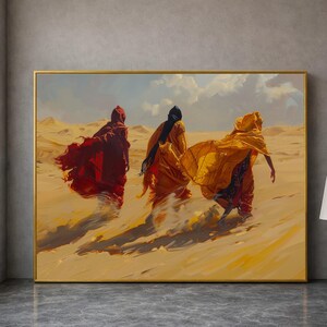 Puede incluir: Una pintura enmarcada representa a tres figuras con túnicas ondeantes que atraviesan un paisaje desértico. Las figuras están vestidas de rojo, amarillo y negro, con el viento ondeando sus ropas. La obra de arte está ambientada sobre un fondo de dunas y un cielo nublado.