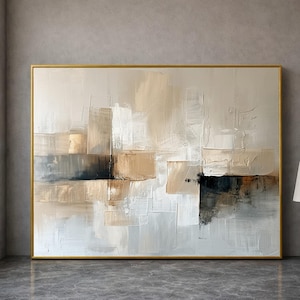 Puede incluir: Pintura de arte abstracto con marco dorado. La obra presenta un diseño texturizado y en capas en tonos neutros de beige, blanco, gris y negro. La composición es una disposición geométrica moderna de formas rectangulares.