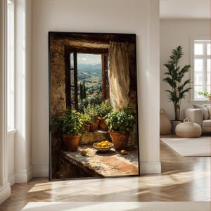 May include: A framed wall art print depicting an open stone window overlooking a rolling landscape. The window sill features three terracotta pots with green plants and a small bowl of yellow lemons, framed by a sheer, light-colored curtain.
