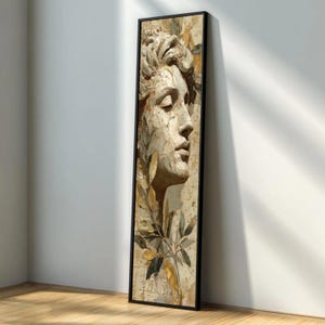 Può includere: Un'opera d'arte da parete alta e rettangolare con cornice, raffigurante una scultura in rilievo testurizzata color beige di un volto umano di profilo. L'opera è decorata con foglie dorate e verde scuro che si estendono dal bordo inferiore.