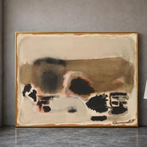 Pode incluir: Pintura abstrata emoldurada em dourado. A obra apresenta um fundo bege com formas castanhas, pretas e cor de pêssego. A pintura tem formato retangular e está exposta em uma parede cinza.