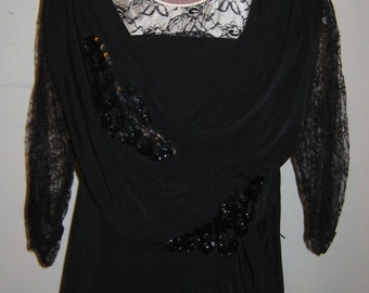 May include: A black dress with long sleeves and a lace neckline. The dress has a beaded design on the bodice and sleeves.