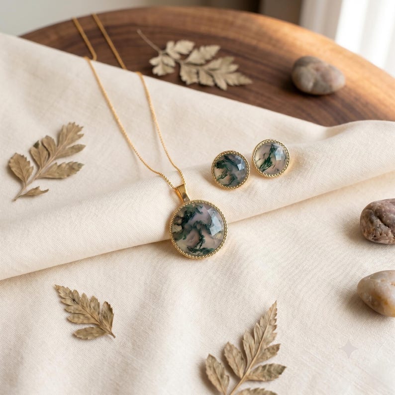 Elegant Moss Agate jewelry set displayed inside a luxury wooden jewelry box with soft pink velvet lining. The set includes a matching round Moss Agate pendant necklace and coordinating stud earrings, each featuring natural green moss-like inclusions within translucent white gemstones. The stones are bezel-set in gold-plated frames, creating a timeless and sophisticated look. This nature-inspired handmade jewelry set is perfect for weddings, bridesmaids, special occasions, and everyday wear,