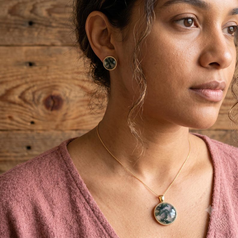 Elegant Moss Agate jewelry set displayed inside a luxury wooden jewelry box with soft pink velvet lining. The set includes a matching round Moss Agate pendant necklace and coordinating stud earrings, each featuring natural green moss-like inclusions within translucent white gemstones. The stones are bezel-set in gold-plated frames, creating a timeless and sophisticated look. This nature-inspired handmade jewelry set is perfect for weddings, bridesmaids, special occasions, and everyday wear,