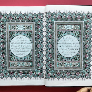 Peut inclure: Livre ouvert présentant des pages avec des écritures arabes et des motifs élaborés de couleur turquoise, rose et or. Les pages sont encadrées de bordures détaillées. Le livre est posé sur une surface rouge.