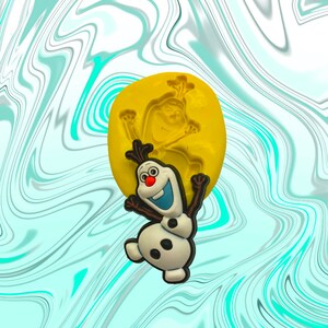 May include: A yellow silicone mold for making a snowman cake topper. The mold is shaped like a snowman with a carrot nose, black eyes, and a black mouth. The snowman is wearing a black top hat and has a black scarf around its neck.